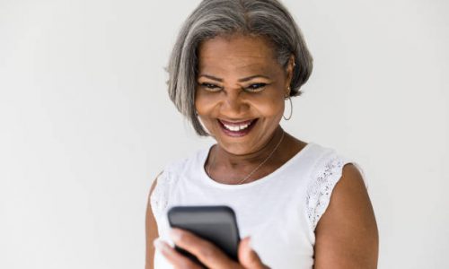 Happy grandmother talks with her grandchildren via smartphone. She is smiling cheerfully.